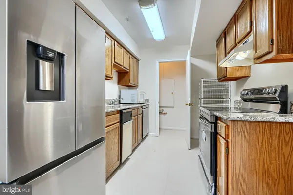 a kitchen with stainless steel appliances granite countertop a refrigerator a stove and a sink