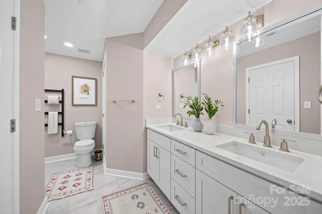 a bathroom with a double vanity sink mirror and toilet