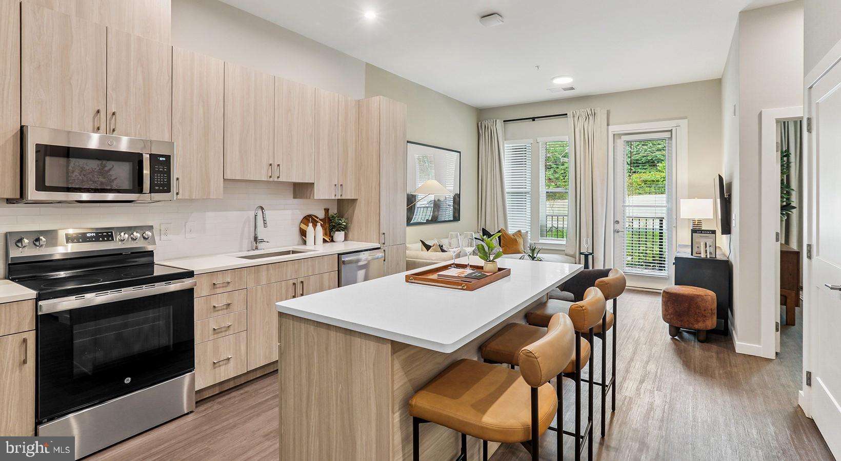 4851 Ellin Road, Unit 128 Hyattsville, MD 20784 - Photo 6 of 14 a kitchen with a stove a sink a microwave a dining table and chairs