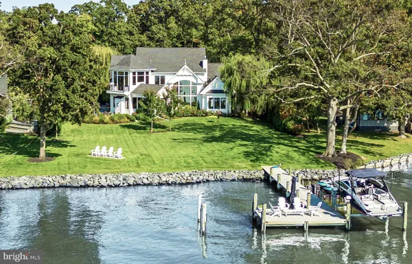 an aerial view of a house with yard and trees in the background