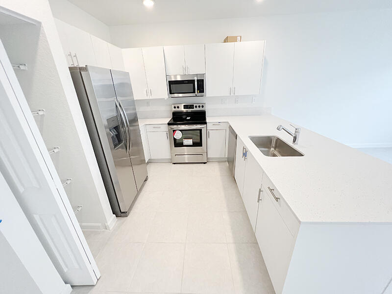13302 Southwest 286th Street, Unit 13302 Homestead, FL 33033 - Photo 2 of 24 a kitchen with white cabinets and stainless steel appliances