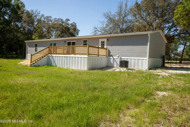 a view of house with backyard and trees in the background