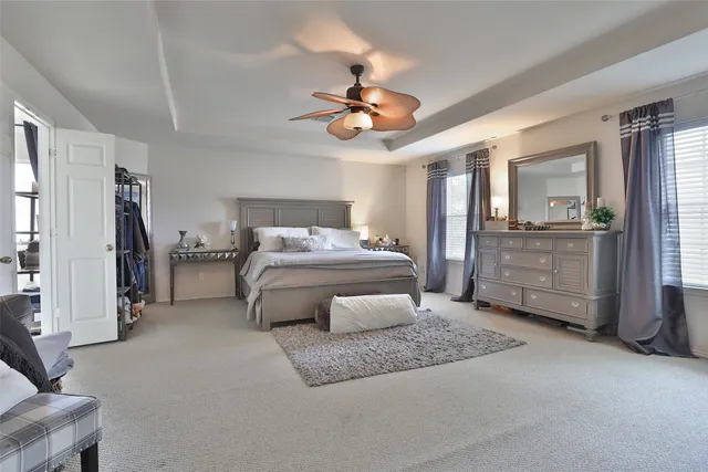 a bedroom with a bed a ceiling fan and a dresser
