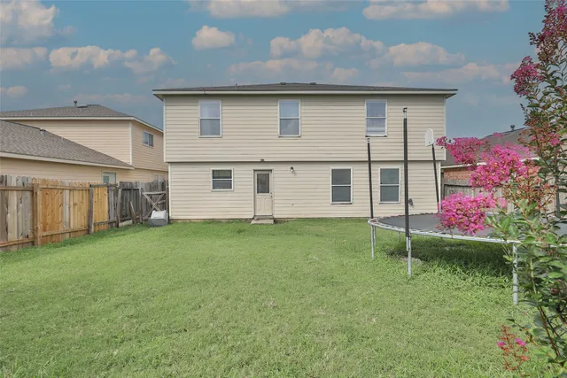 a backyard of a house with plants and large tree