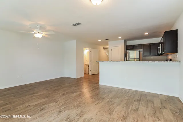 a view of a kitchen with kitchen island a sink wooden floor and a refrigerator