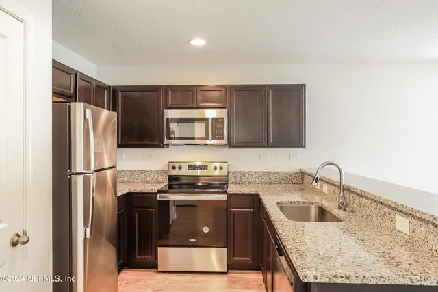 a kitchen with granite countertop a sink stove and refrigerator