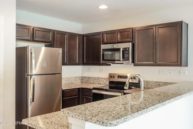 a kitchen with granite countertop a refrigerator and a sink