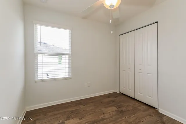 an empty room with wooden floor cabinet and windows