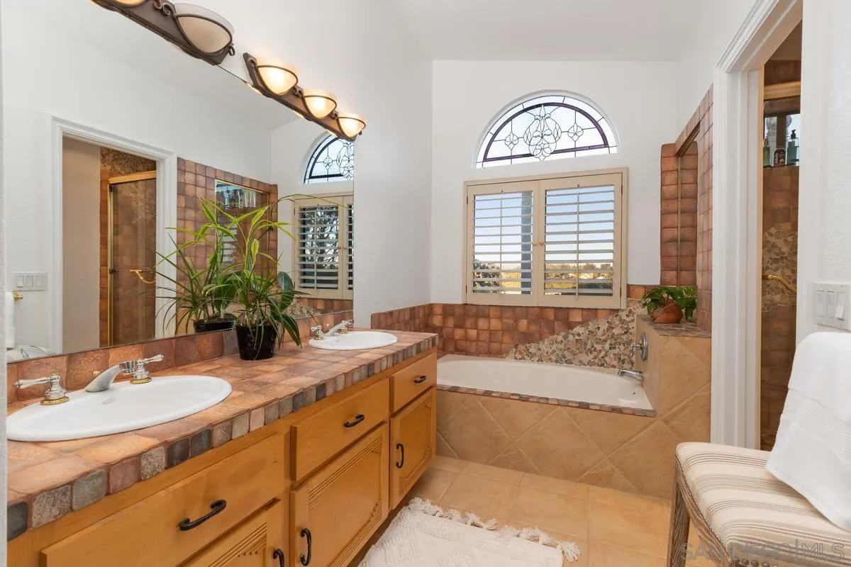 445 Via Savoy Encinitas, CA 92024 - Photo 18 of 39 a spacious bathroom with a granite countertop tub mirror and window
