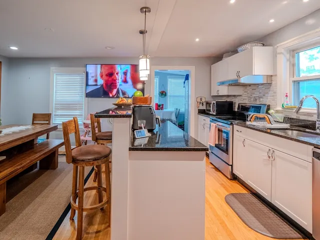 a kitchen view with stainless steel appliances kitchen island granite countertop a stove and a sink