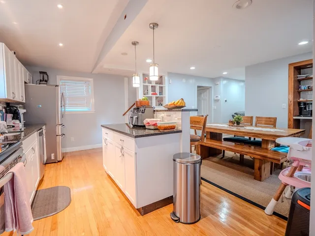 a kitchen with stainless steel appliances a stove a sink dishwasher and a dining table with wooden floor