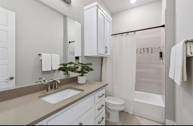 a bathroom with a granite countertop sink toilet and shower