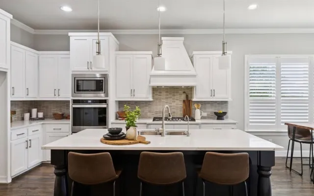 a kitchen with stainless steel appliances a white table chairs and a refrigerator