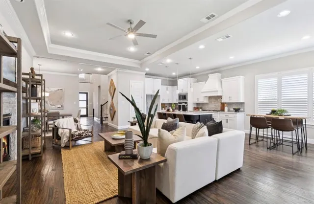 a living room with lots of furniture kitchen view and a wooden floor