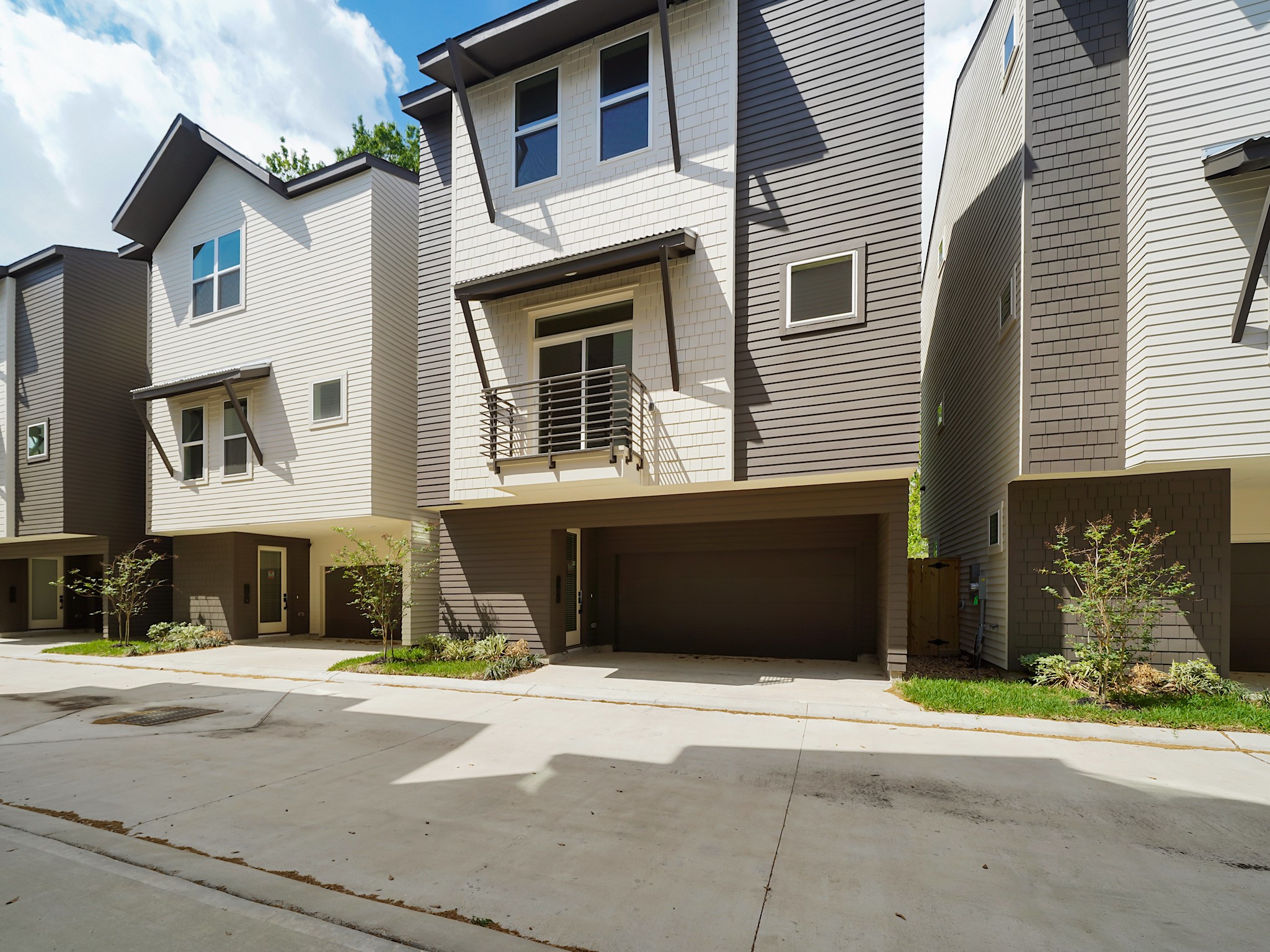 861 Rachel Street, Unit E Houston, TX 77091 - Photo 27 of 29 Modern three-story townhouse with a two-car garage, sleek exterior design, and a small front yard, situated in a row of similar homes.