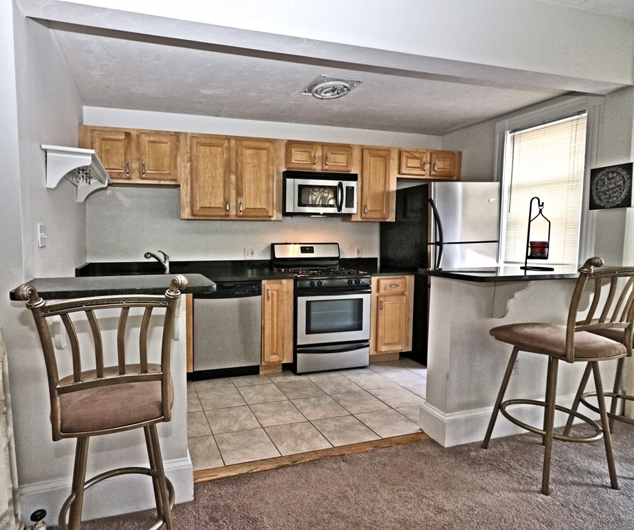 53 Trident Avenue, Unit 103 Winthrop, MA 02152 - Photo 12 of 16 a kitchen with stainless steel appliances granite countertop a stove top oven and a refrigerator