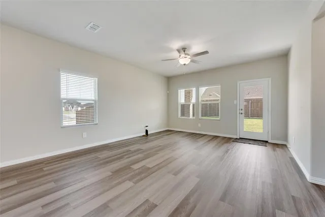 a view of an empty room with a window and wooden floor