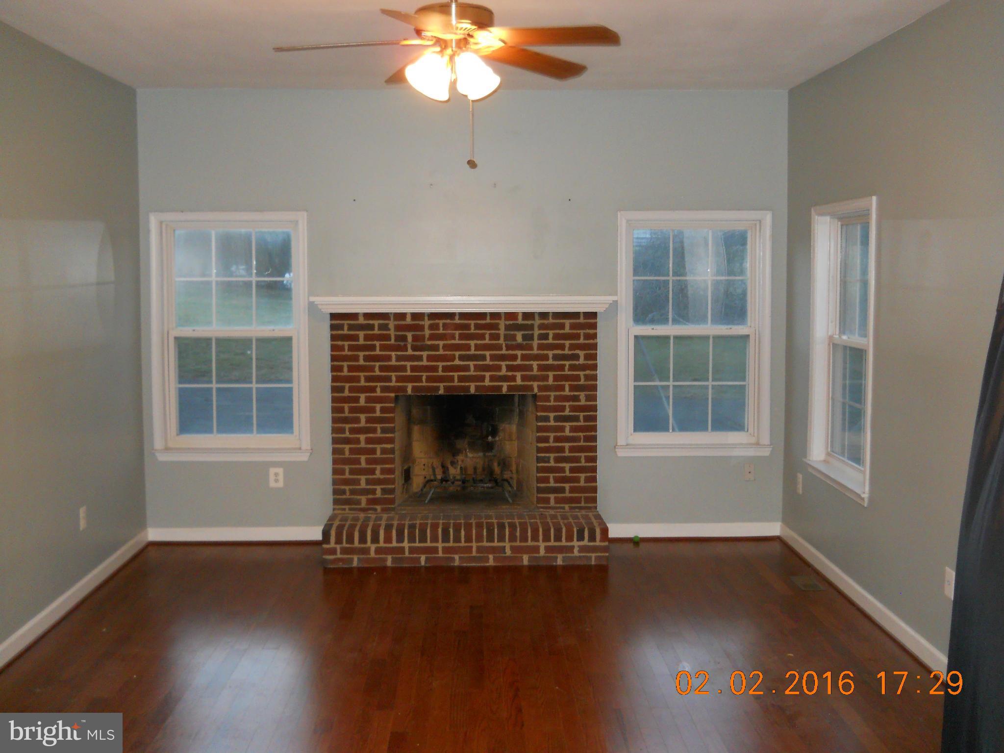 3405 Evans Road Huntingtown, MD 20639 - Photo 7 of 16 a living room with a fireplace wooden floor and a window