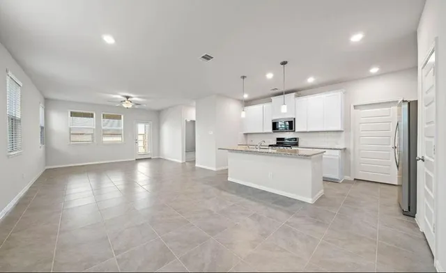 a view of a kitchen with refrigerator and white cabinets