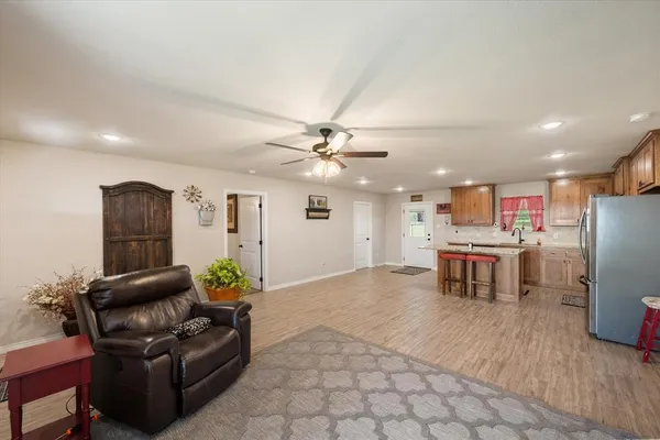 a kitchen with stainless steel appliances kitchen island granite countertop a refrigerator a stove a sink a dining table and chairs with wooden floor