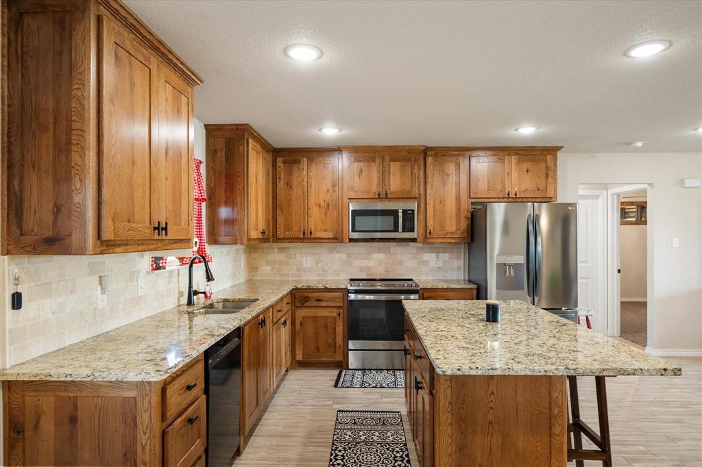 2004 Brown Loop Poolville, TX 76487 - Photo 17 of 36 a kitchen with stainless steel appliances granite countertop a sink stove and refrigerator