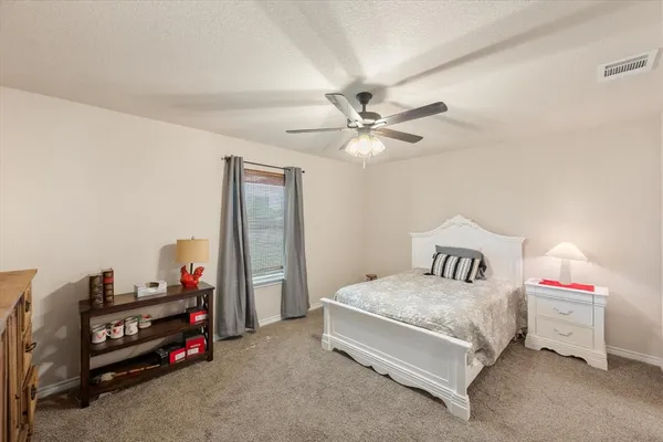 an empty room with chandelier fan and windows