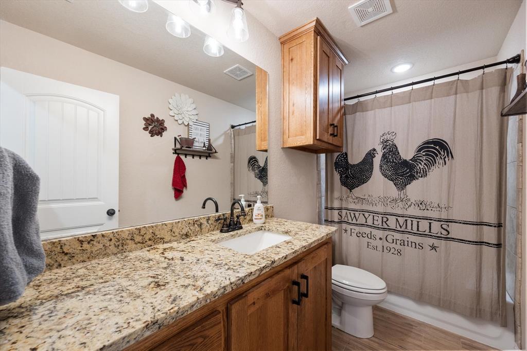 2004 Brown Loop Poolville, TX 76487 - Photo 26 of 36 a bathroom with a granite countertop sink a toilet and a mirror