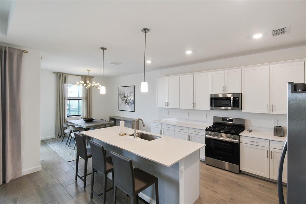 15025 Sea Salt Way Bradenton, FL 34211 - Photo 31 of 64 a kitchen with a sink a stove a refrigerator and white cabinets
