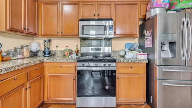 a kitchen with stainless steel appliances granite countertop a refrigerator and a stove top oven
