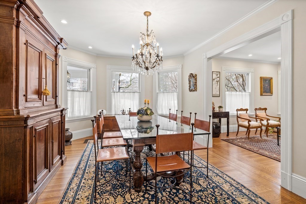 351 Otis Street Newton, MA 02465 - Photo 8 of 30 a dining room with wooden floor a chandelier a wooden table and chairs