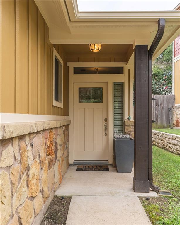 6708 Menchaca Road, Unit 14 Austin, TX 78745 - Photo 20 of 22 Covered entry with natural stone veneer, a panel door with integrated glass, and a transom window