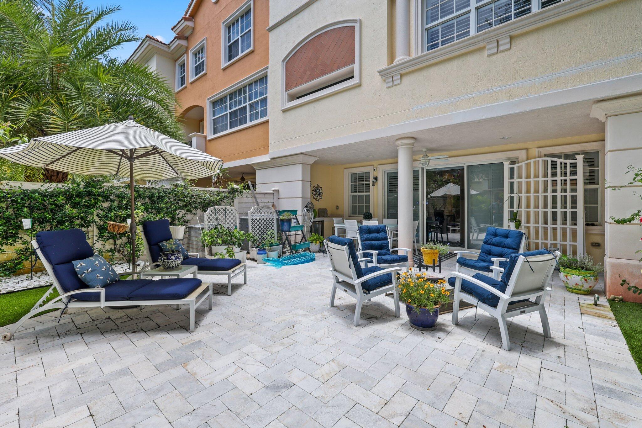 5530 Northeast Trieste Terrace, Unit 5530 Boca Raton, FL 33487 - Photo 19 of 57 a view of a patio with a table and chairs under an umbrella with a fire pit