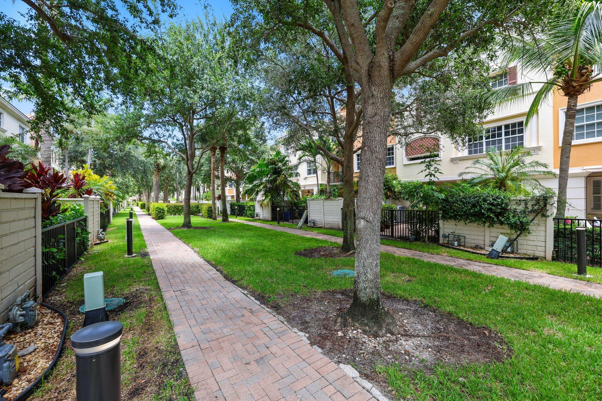 5530 Northeast Trieste Terrace, Unit 5530 Boca Raton, FL 33487 - Photo 21 of 57 a front view of a house with a yard and large trees
