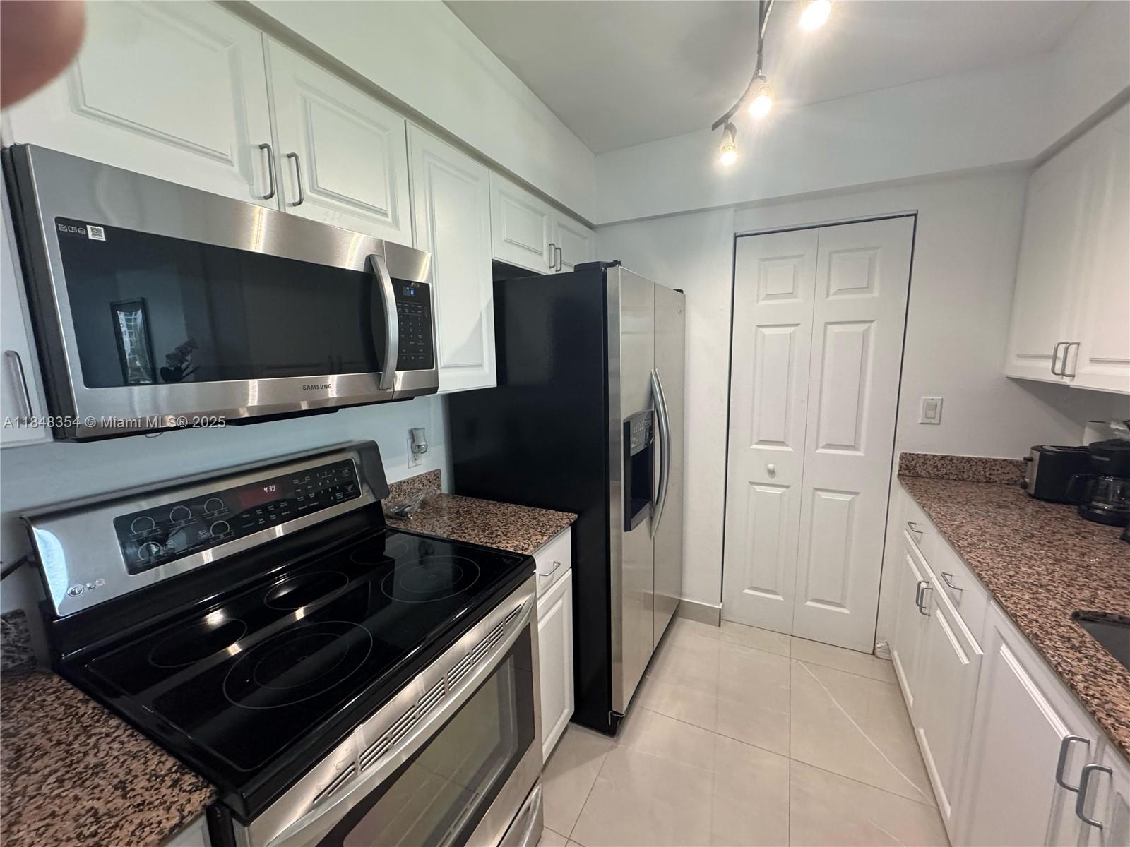 1155 Brickell Bay Drive, Unit 307 Miami, FL 33131 - Photo 13 of 23 a kitchen with stainless steel appliances kitchen island granite countertop a stove and a refrigerator