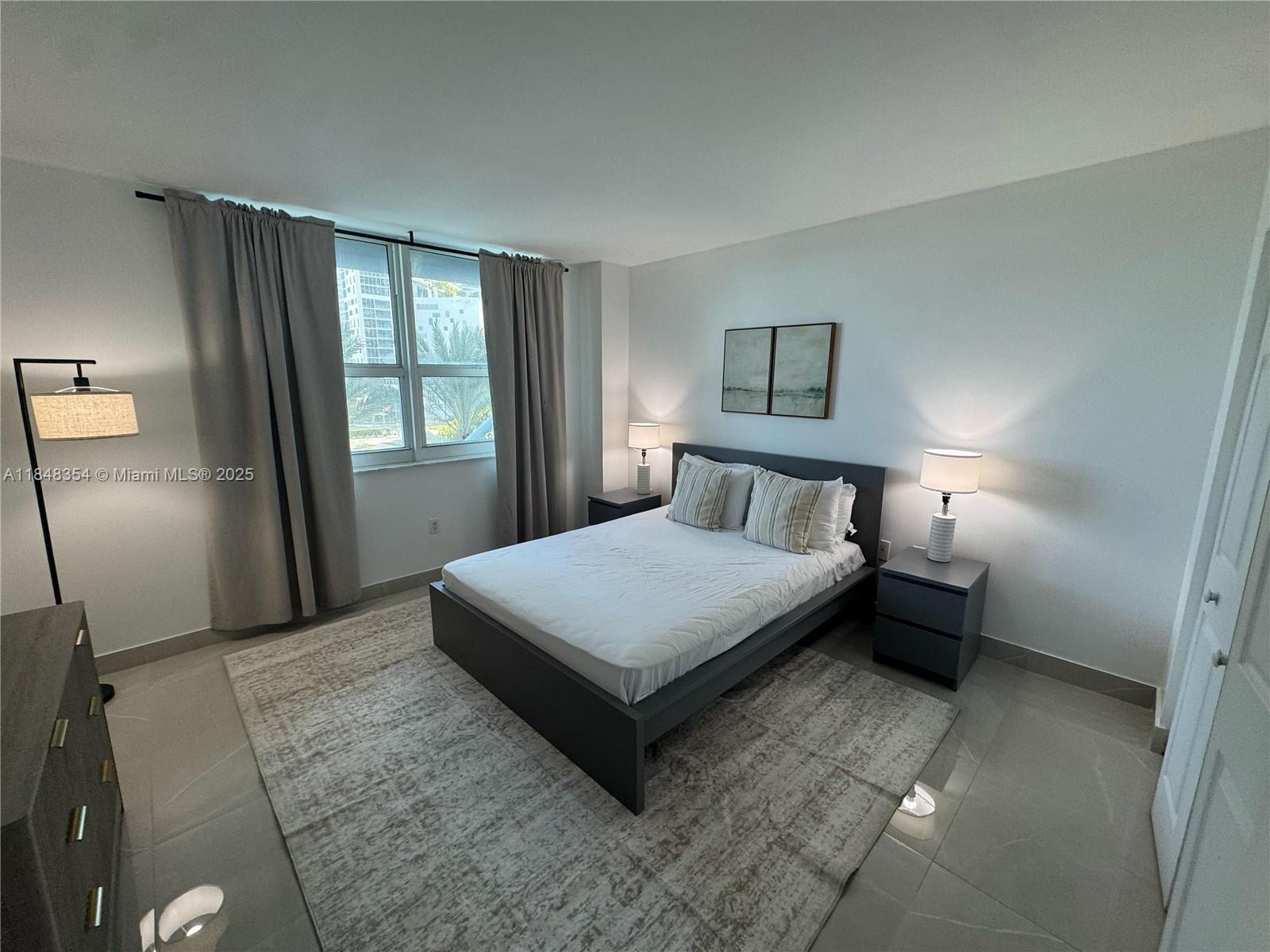 1155 Brickell Bay Drive, Unit 307 Miami, FL 33131 - Photo 14 of 23 a bedroom with a bed lamp and window