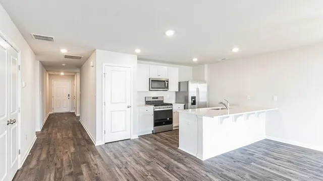 a kitchen with a sink wooden floor and stainless steel appliances