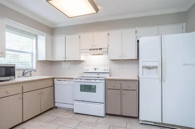 a kitchen with white cabinets and white appliances
