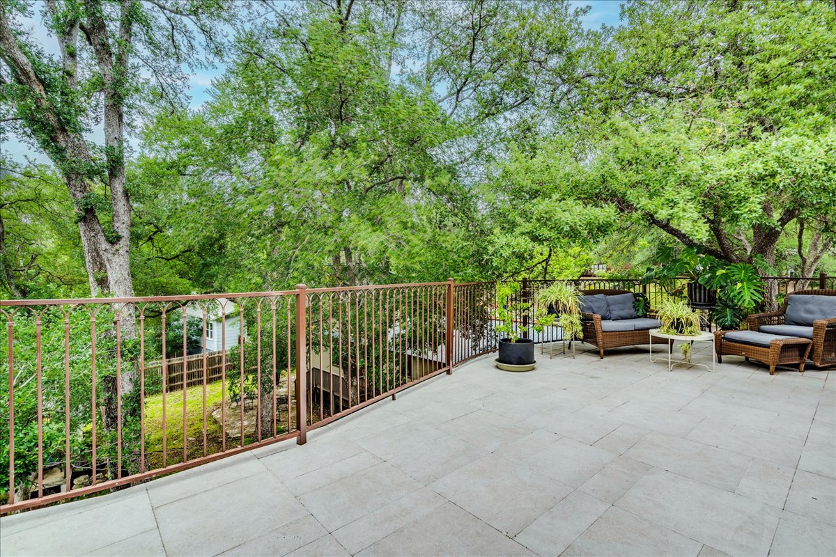 3012 South 4th Street, Unit B Austin, TX 78704 - Photo 28 of 40 Expansive elevated patio featuring a tiled surface and wrought iron railing, surrounded by mature trees