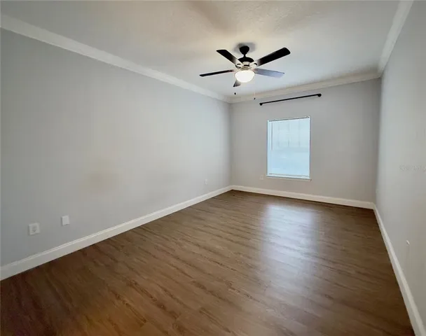 a view of empty room with wooden floor and fan