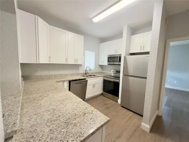 a kitchen with granite countertop white cabinets and white stainless steel appliances