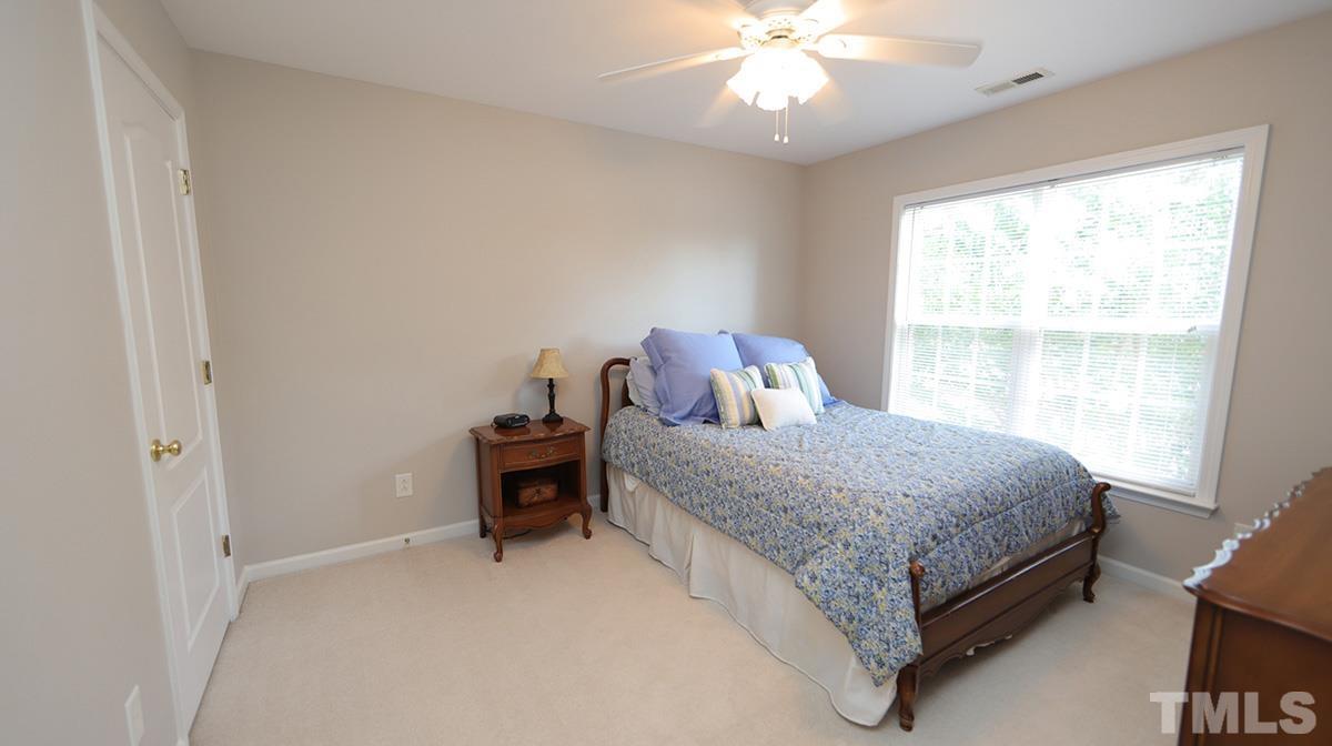 5410 Wind Mountain Lane Raleigh, NC 27613 - Photo 10 of 13 a bedroom with a bed and a chandelier
