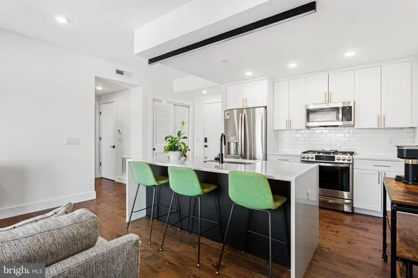 a kitchen with stainless steel appliances a dining table chairs and refrigerator