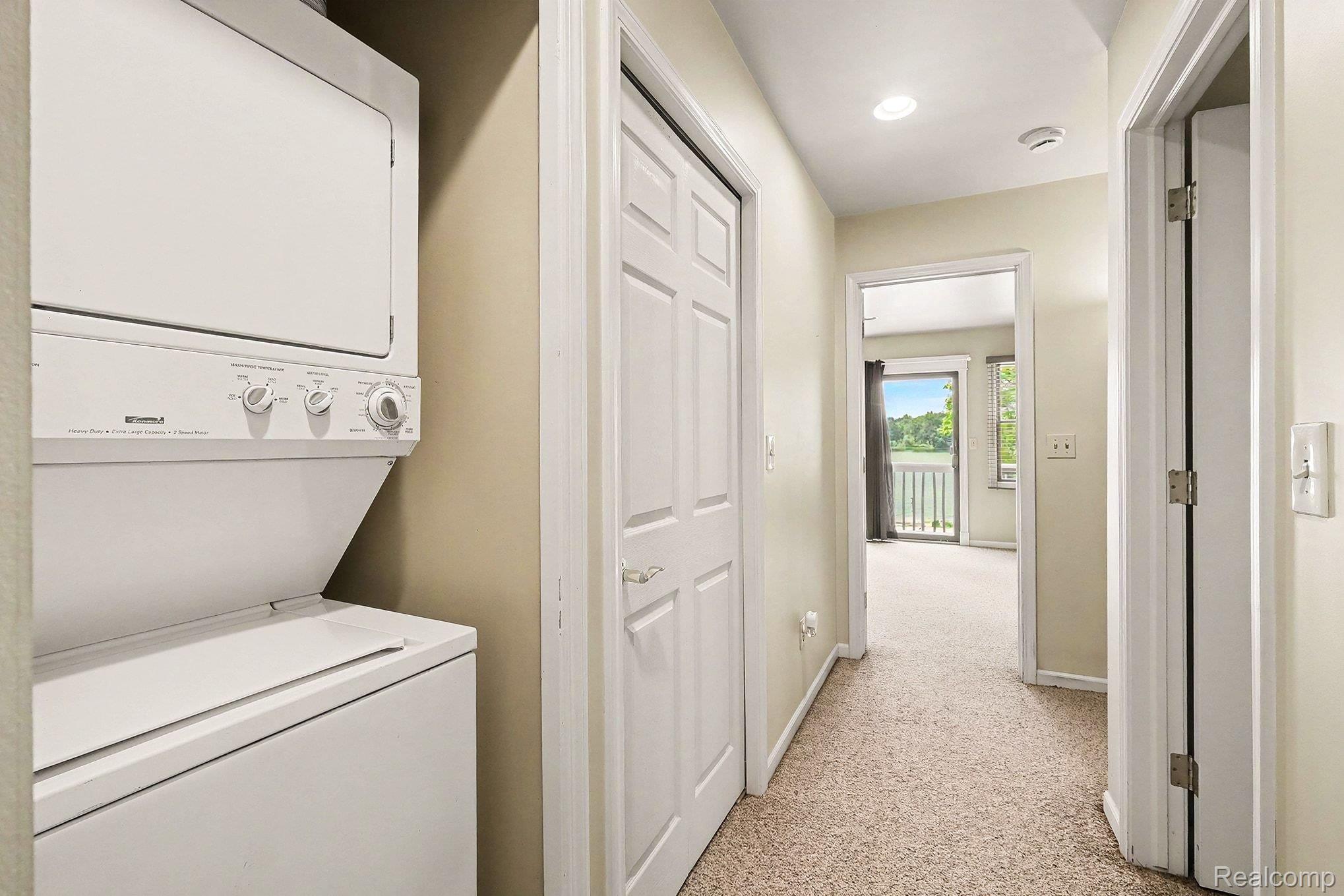 16059 Murray Road Byron, MI 48418 - Photo 21 of 32 Hallway featuring a stacked washer and dryer, textured carpeting, multiple white panel doors, and recessed lighting
