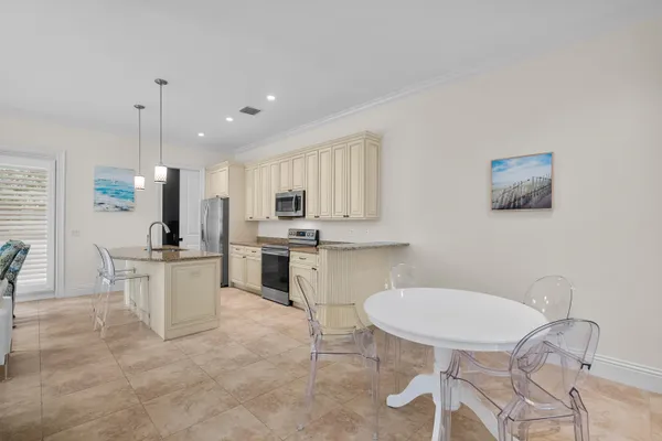 a kitchen with white cabinets and chairs