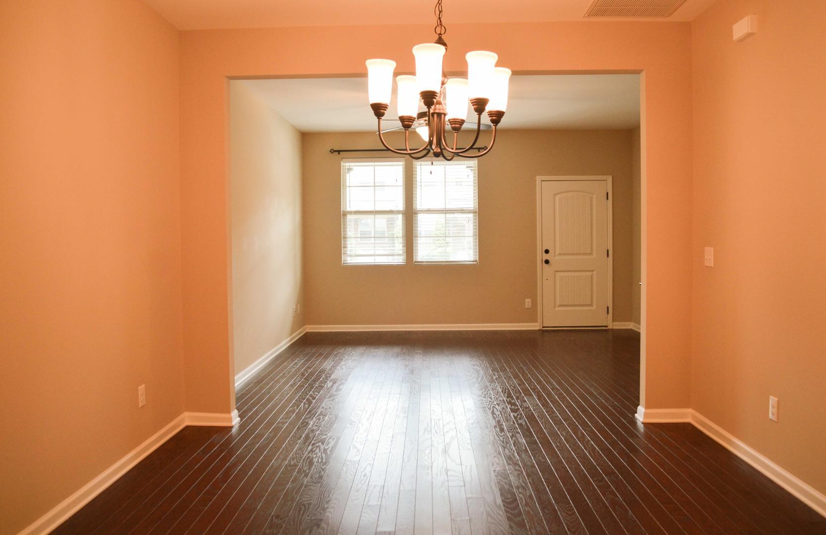 720 Wickham Ridge Road Apex, NC 27539 - Photo 4 of 24 an empty room with wooden floor chandelier and windows