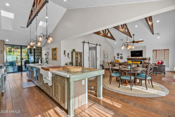 a view of a dining room and livingroom with furniture wooden floor kitchen view and a chandelier
