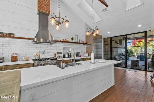 a kitchen with stainless steel appliances granite countertop a sink dishwasher a stove and white cabinets with wooden floor