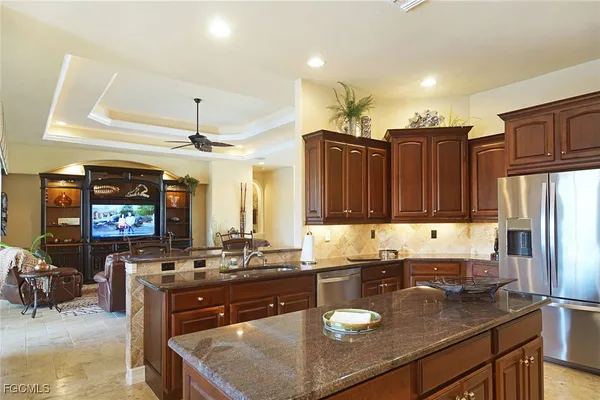 a kitchen with stainless steel appliances granite countertop a refrigerator a stove and a sink with wooden cabinets