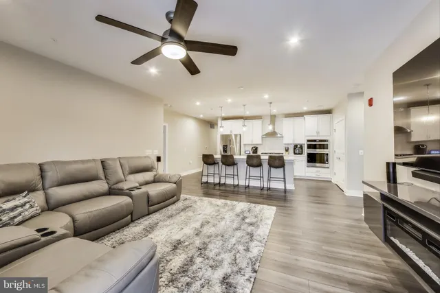 a living room with furniture kitchen view and a wooden floor