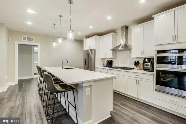 a kitchen with stainless steel appliances a white table chairs refrigerator and cabinets